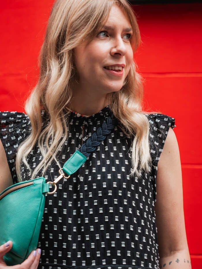 Blonde woman wearing frilly dotted blouse and leather crossbody bag